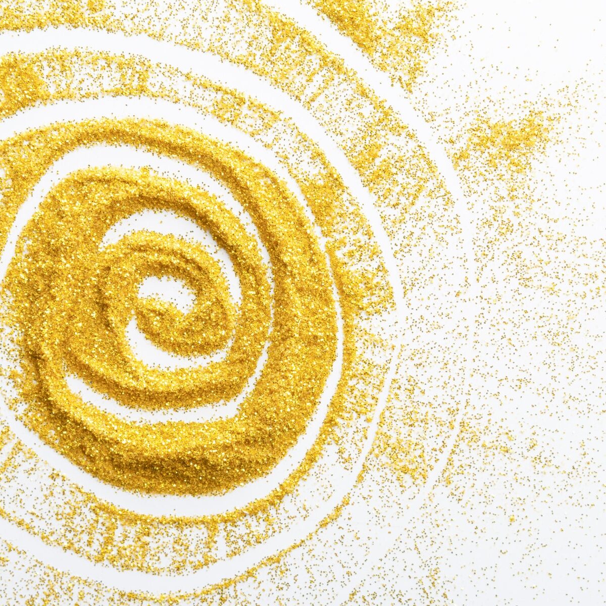 Sand painting concept. Golden glitter sand texture spread over white surface with sun shape, abstract background, top view. Yellow dusty shimmer decoration, shiny and sparkling.